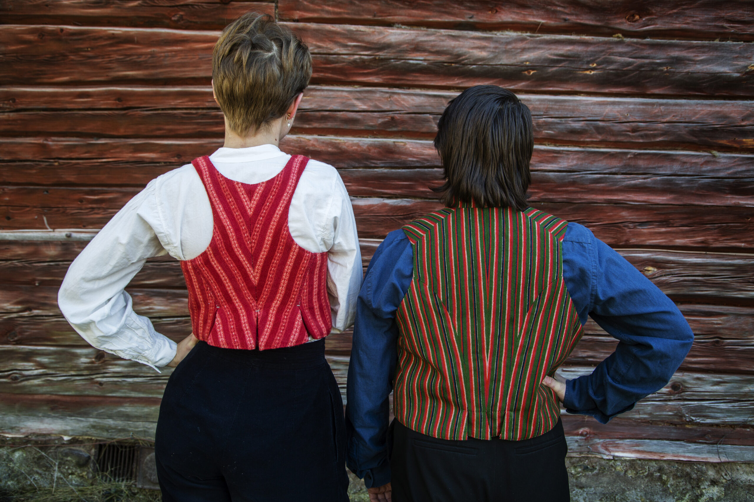 Two people in folk costume with their back towards the viewer.